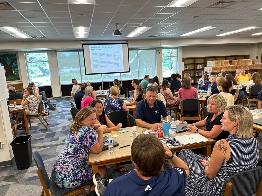 Several tables of people at a P2 event in a library