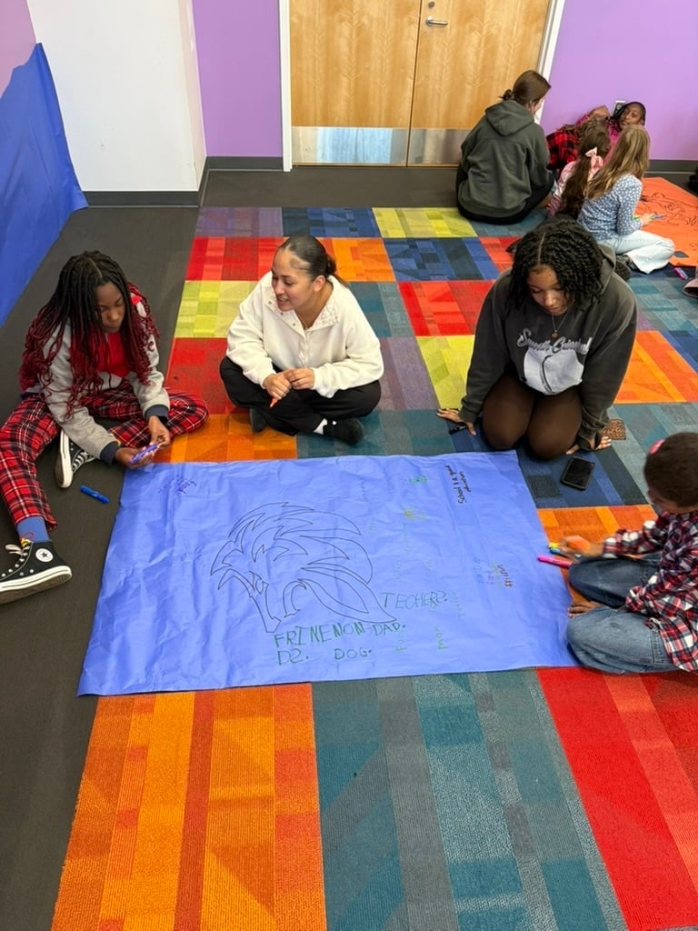 students-gathered-around-blue-poster-sitting-on-colorful-carpet