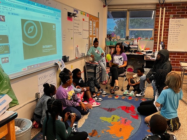 students in front of weekly slides with integrity on the board