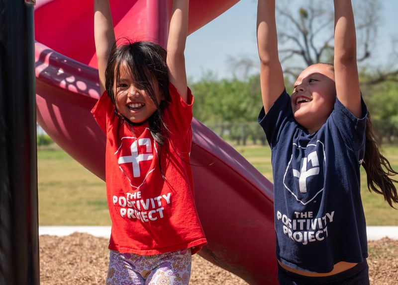 girls hanging from monkey bars on a playground