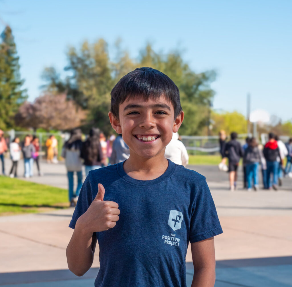 A child giving a thumbs up and smiling