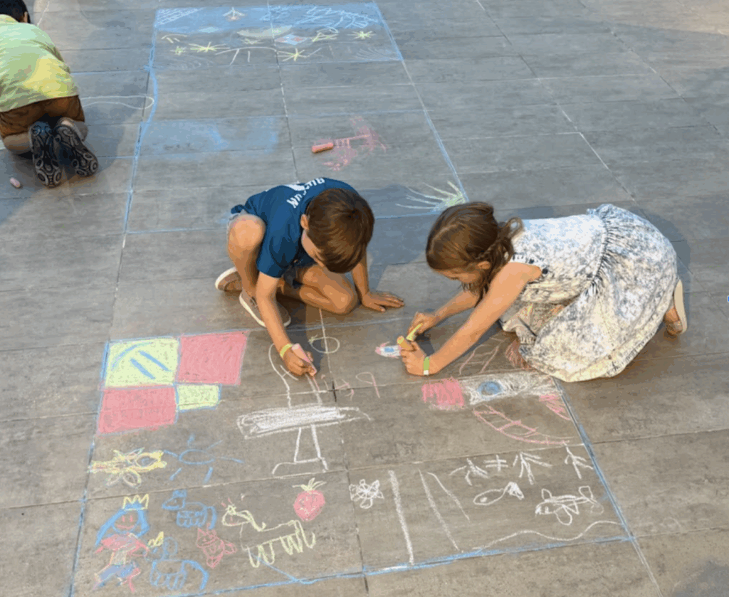 A boy and a girl drawing in sidewalk chalk