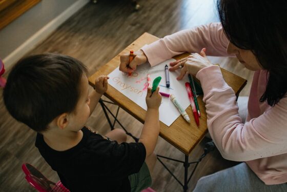 A small boy and his mother coloring with crayons together