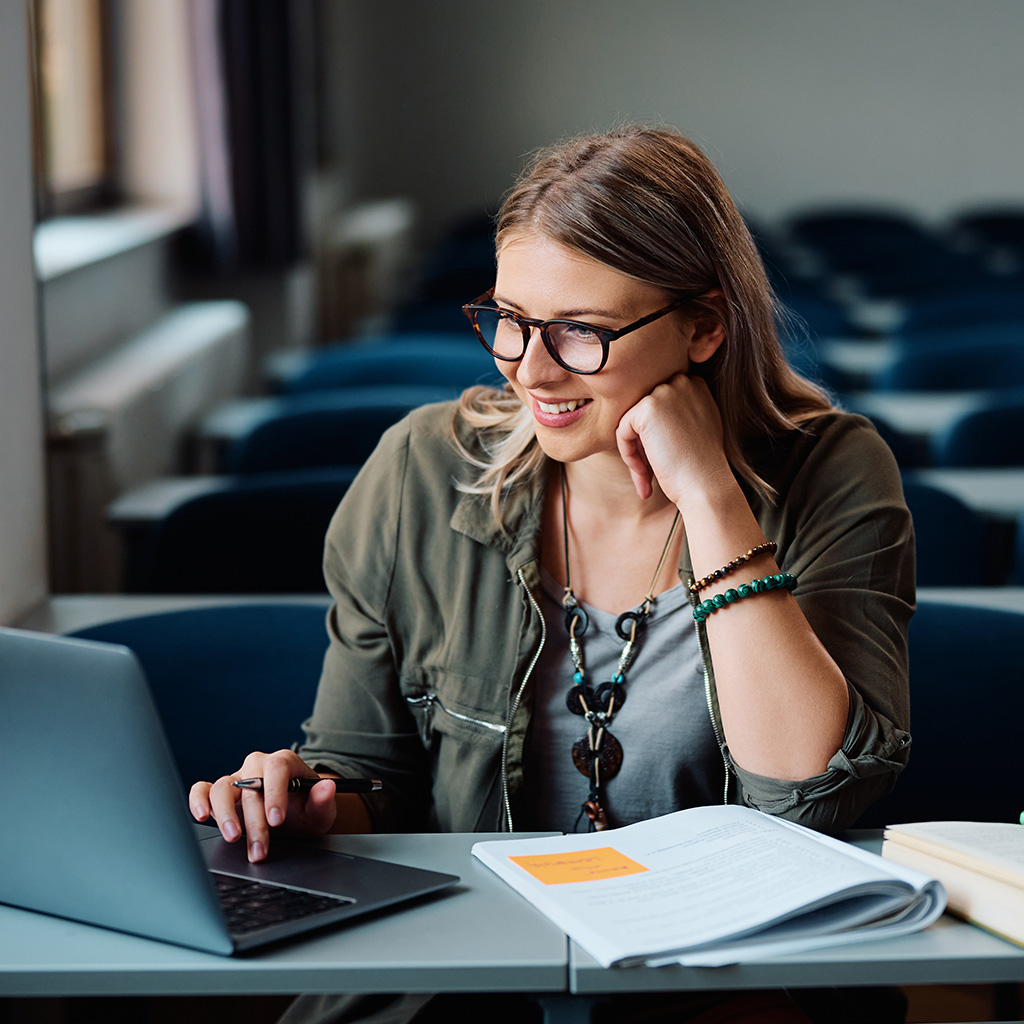 woman looking at a computer with a notebook