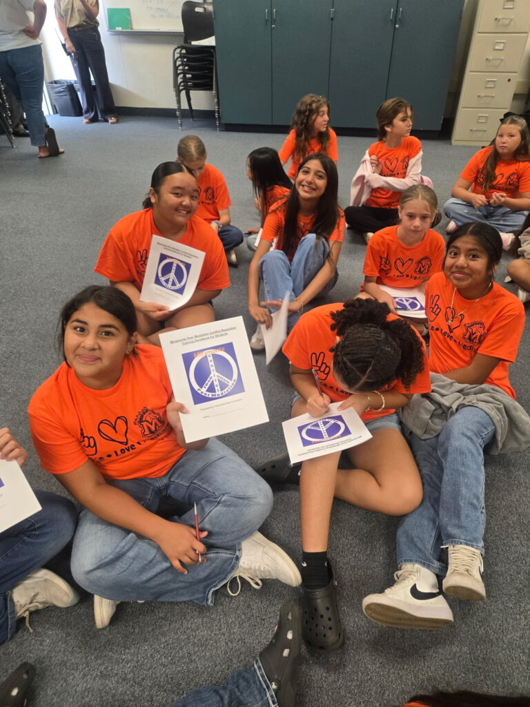 students-in-orange-shirts-sitting-on-class-floor