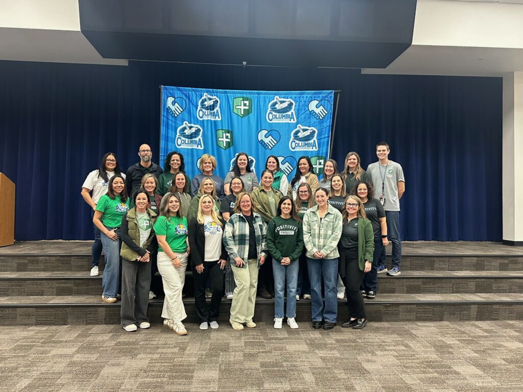 school-staff-posing-in-front-of-blue-banner