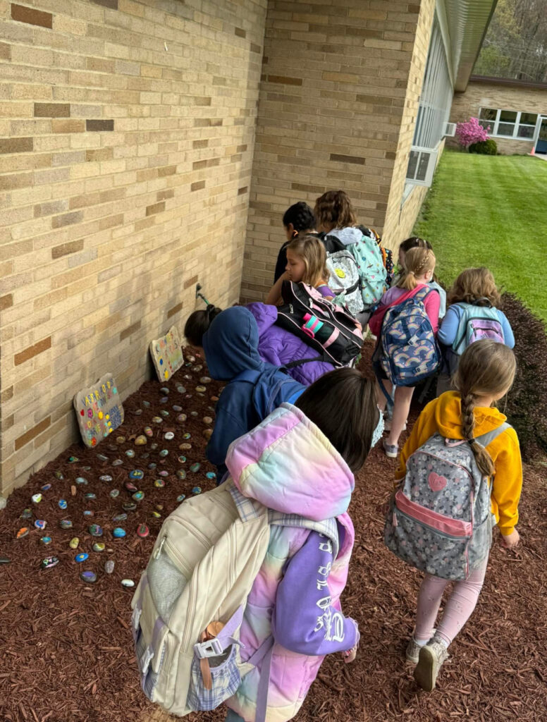 young-students-placing-painted-rocks-in-garden