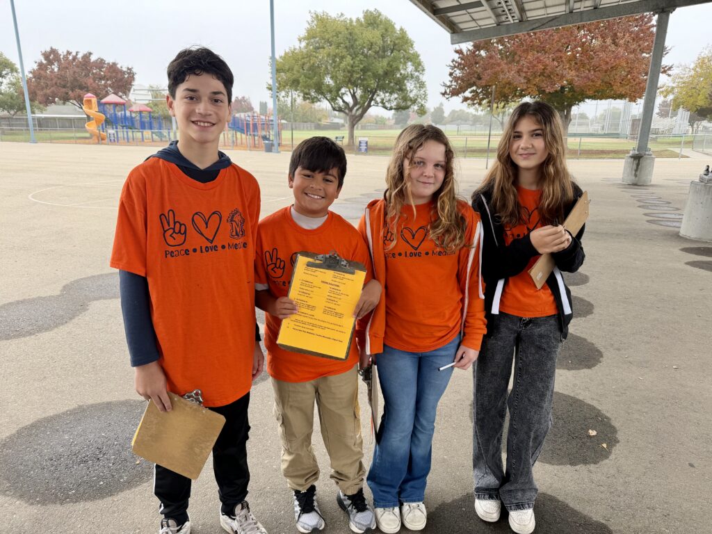 four-students-outside-school-holding-clipboards