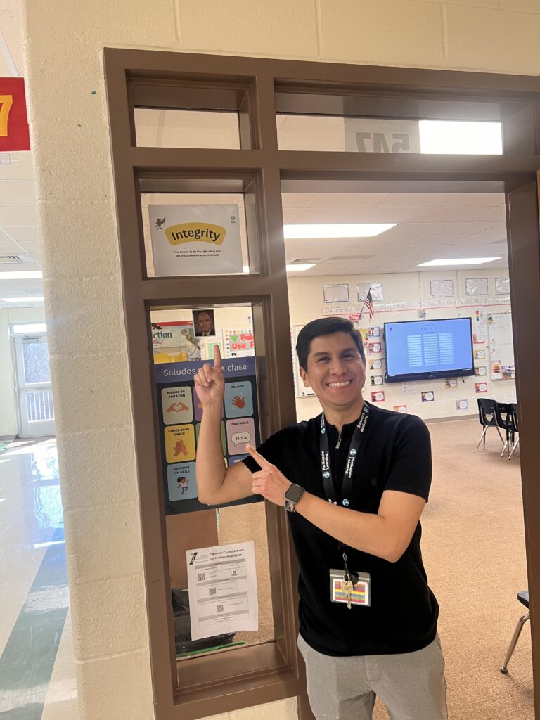 male-teacher-pointing-at-sign-on-doorway