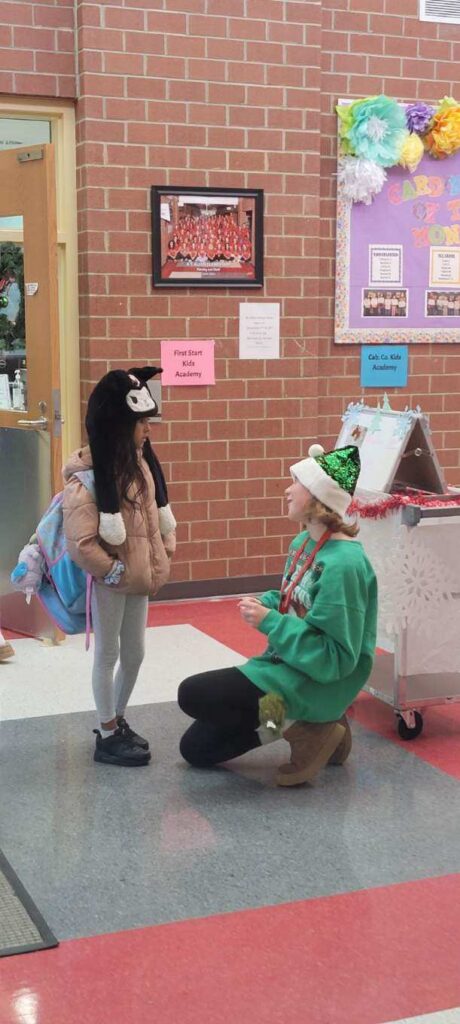 girl-in-green-shirt-kneeling-talking-to-young-girl-standing