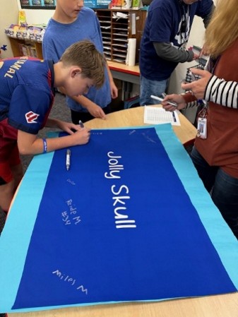 students-writing-on-blue-sign