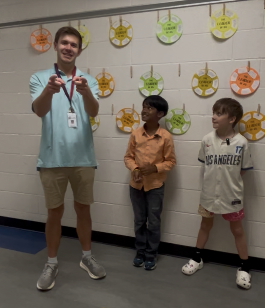 school-counselor-pointing-at-camera-with-kids-nearby