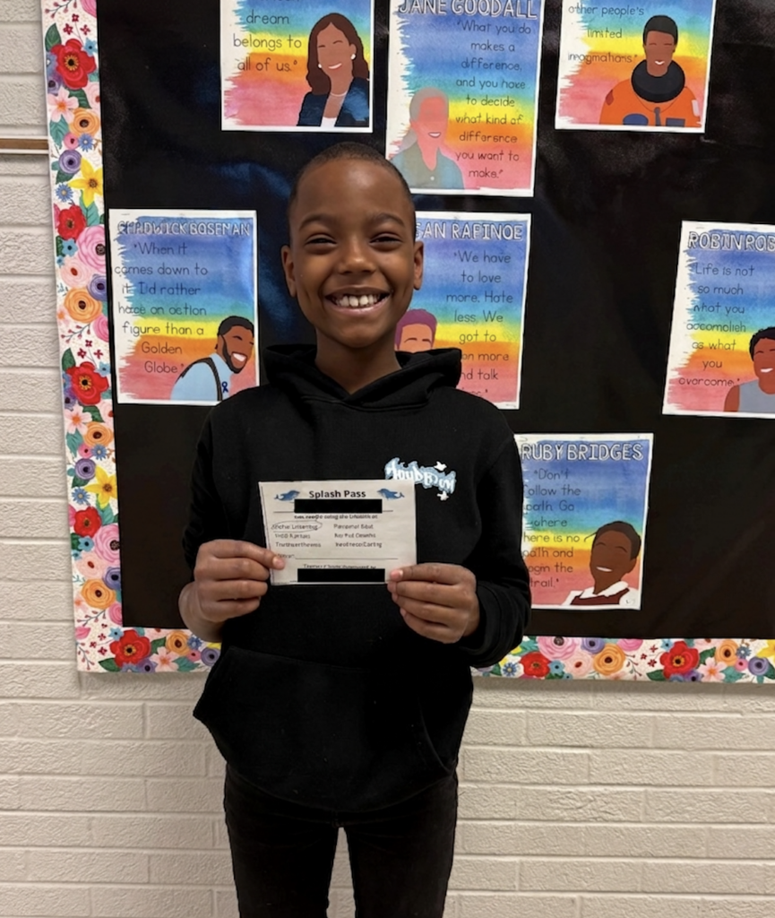 smiling-young-student-wearing-all-black-holding-up-small-piece-of-white-paper